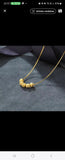 Collier en acier inoxydable doré, orné de cinq perles finement texturées. Un bijou délicat et lumineux, facile à porter au quotidien.