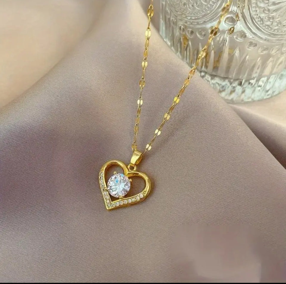 Sublimez votre tenue avec ce collier raffiné en acier inoxydable doré, conçu pour allier élégance et durabilité. Son pendentif en forme de cœur ajouré symbolise l’amour et la délicatesse, rehaussé d’une pierre centrale scintillante qui capte la lumière.
