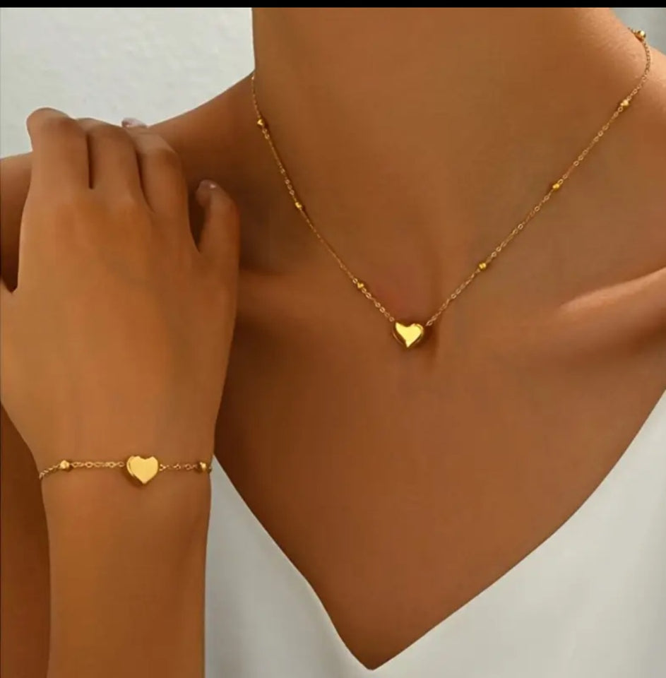 Ensemble collier et bracelet en acier inoxydable doré, orné de délicats pendentifs en forme de cœur. Sa chaîne fine et élégante, rehaussée de petites perles dorées, apporte une touche de féminité et de raffinement.