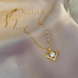 Sublimez votre tenue avec ce collier raffiné en acier inoxydable doré, conçu pour allier élégance et durabilité. Son pendentif en forme de cœur ajouré symbolise l’amour et la délicatesse, rehaussé d’une pierre centrale scintillante qui capte la lumière.