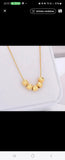 Collier en acier inoxydable doré, orné de cinq perles finement texturées. Un bijou délicat et lumineux, facile à porter au quotidien.