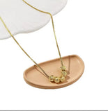 Collier en acier inoxydable doré, orné de cinq perles finement texturées. Un bijou délicat et lumineux, facile à porter au quotidien.